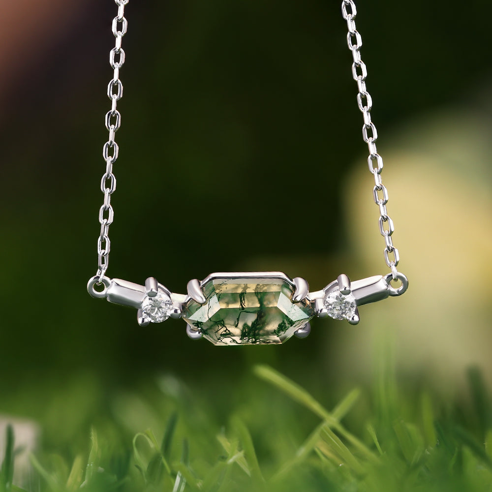 Silver necklace with green gemstone and two smaller stones on a grassy background